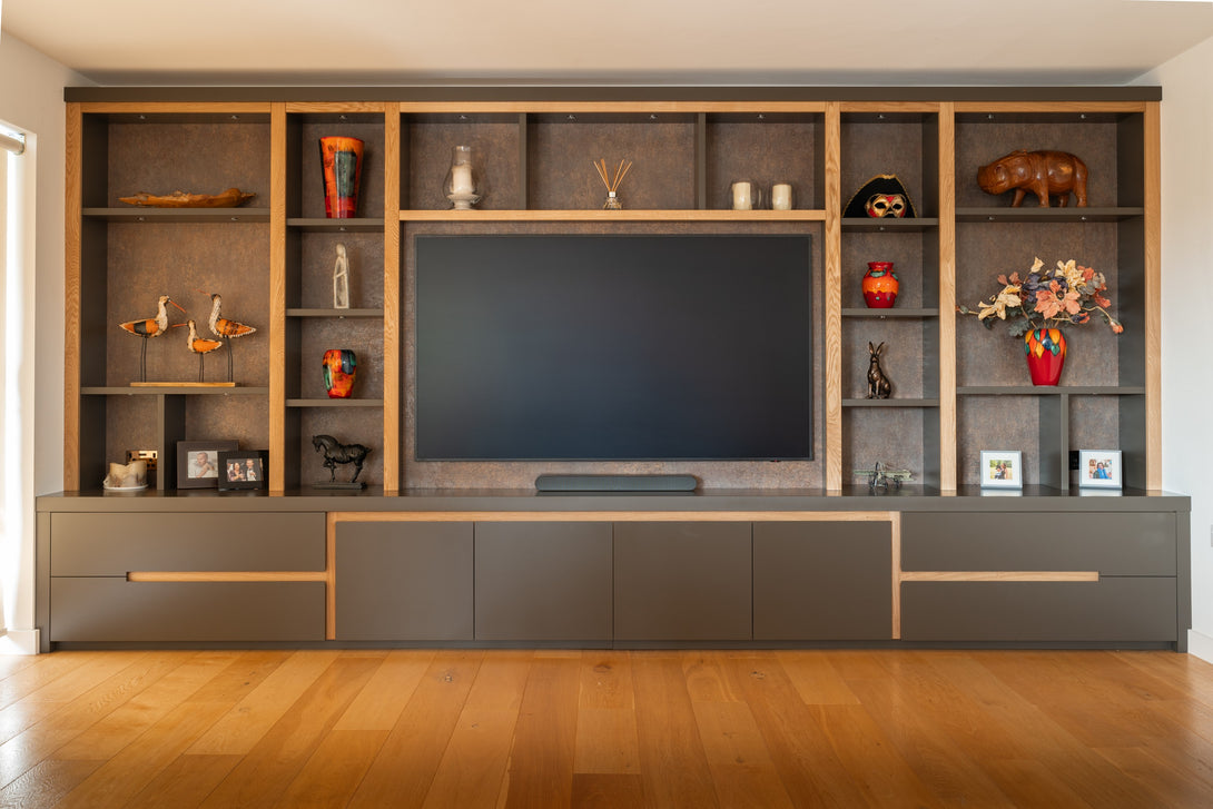A straight-on view of the bespoke lounge media wall by Drew Furniture, with the television off, highlighting the symmetrical design and combination of oak and grey finishes.