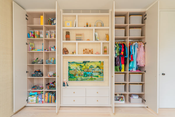 A full view of the bespoke playroom storage unit with all doors open, revealing three sections: toy and craft storage on the left, a central display with drawers, and a dress-up wardrobe on the right.