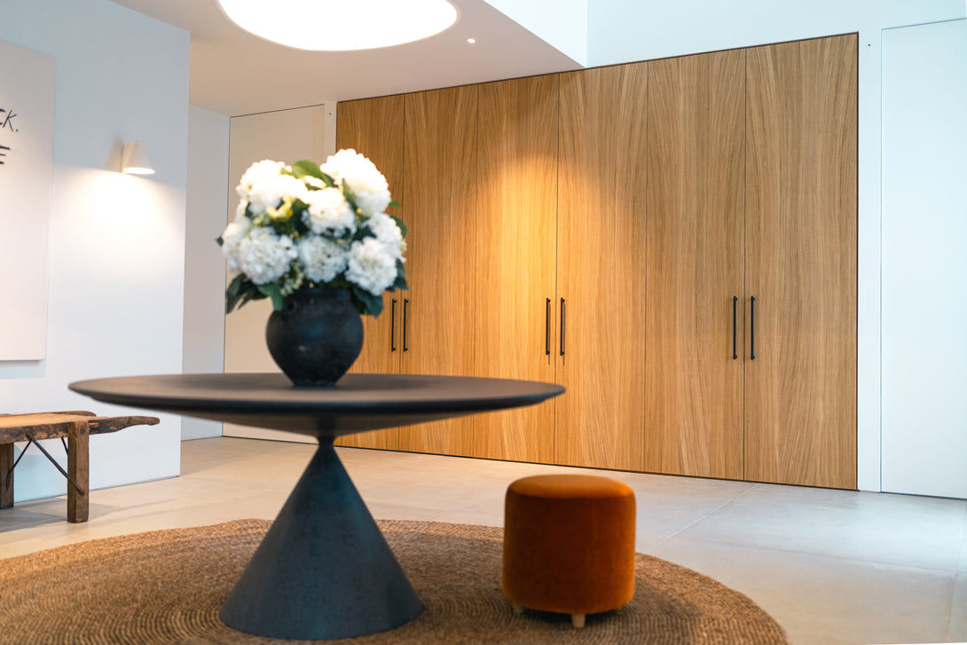 A view of the minimalist entrance hall focusing on the floor-to-ceiling bespoke oak wardrobes, which provide a warm, natural backdrop to the modern decor.