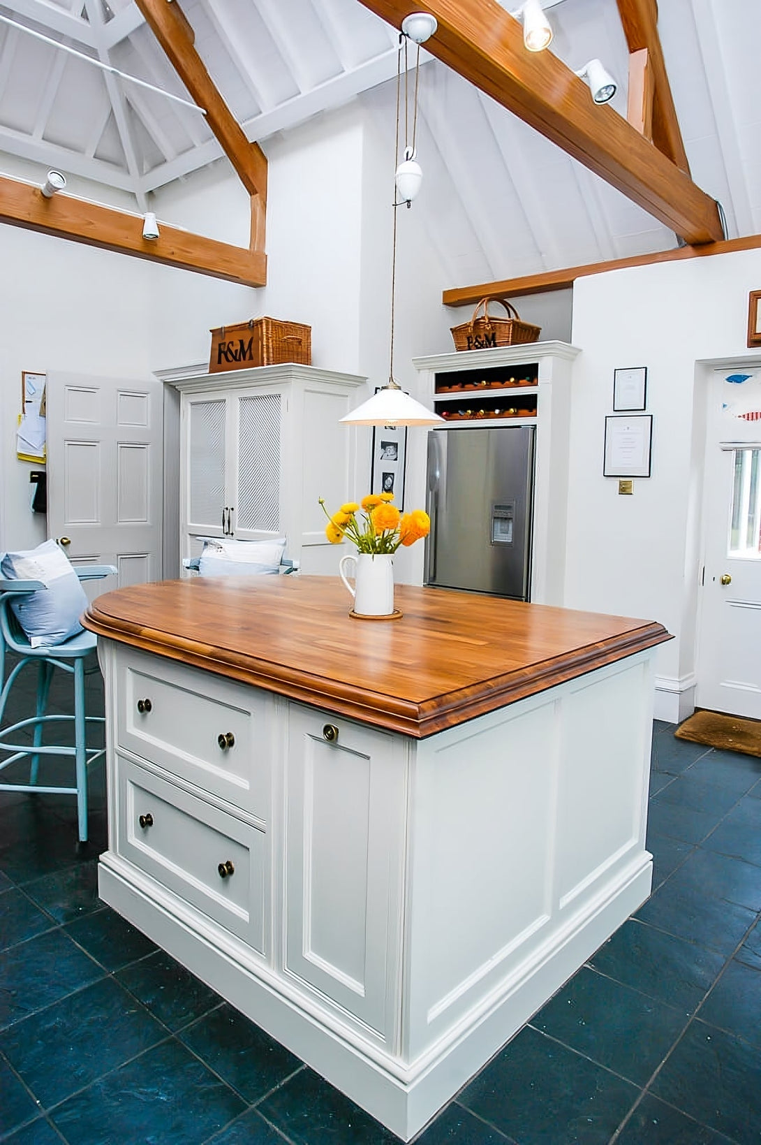 The back of the cream kitchen island showing drawer storage, with the bespoke larder cupboard and integrated wine rack visible in the background.