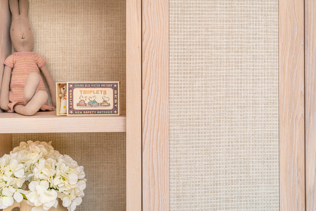 A close-up showing the texture of the woven rattan inlay on a wardrobe door next to an open display shelf with toys.