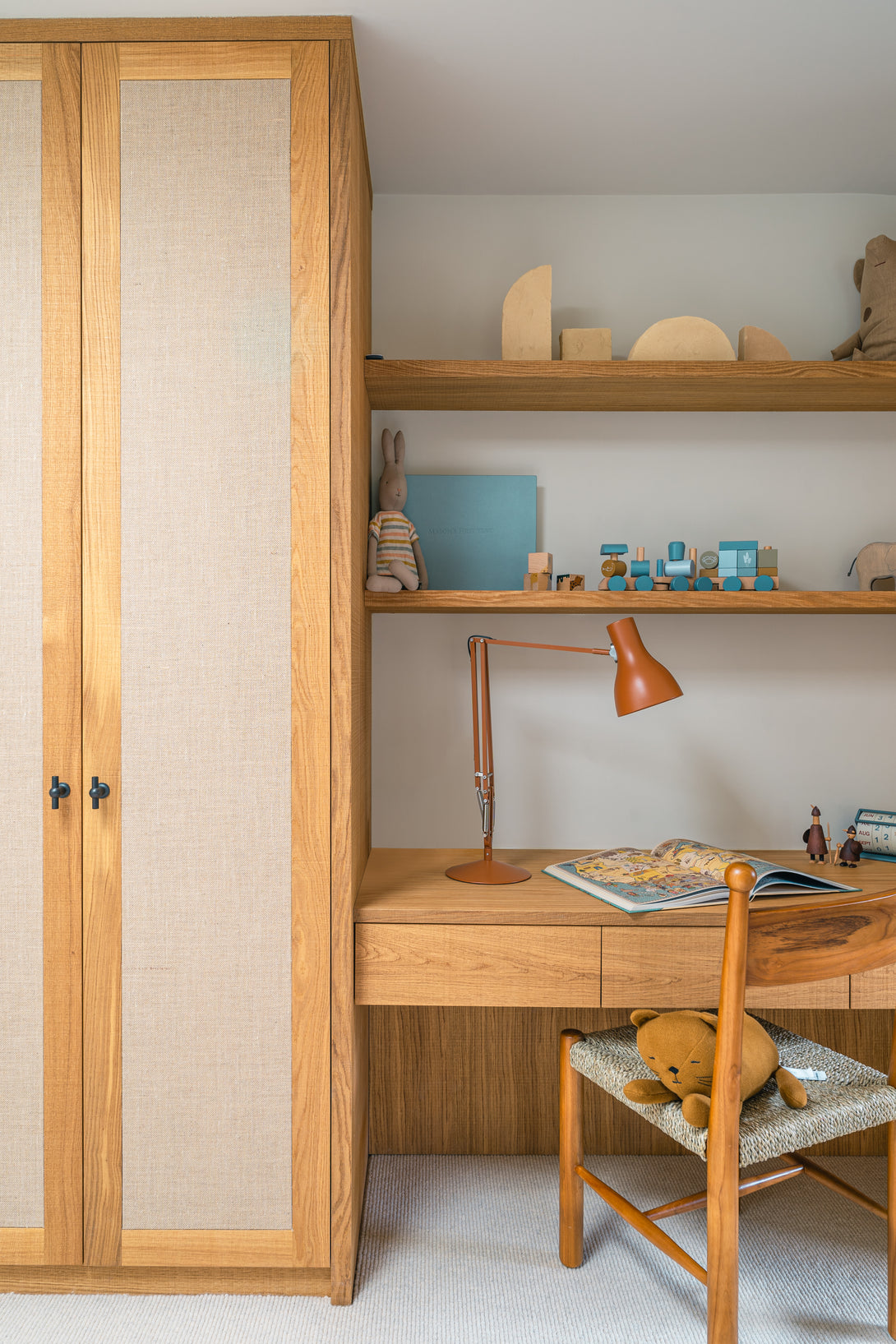 A detailed view of the custom-built desk area, featuring a solid oak desktop, integrated shelving, and elegant brushed brass hardware.