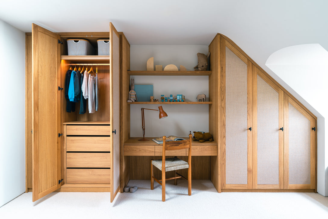 An open wardrobe in the son's bedroom showing the natural oak interior with clothes hanging and neatly arranged shelves.