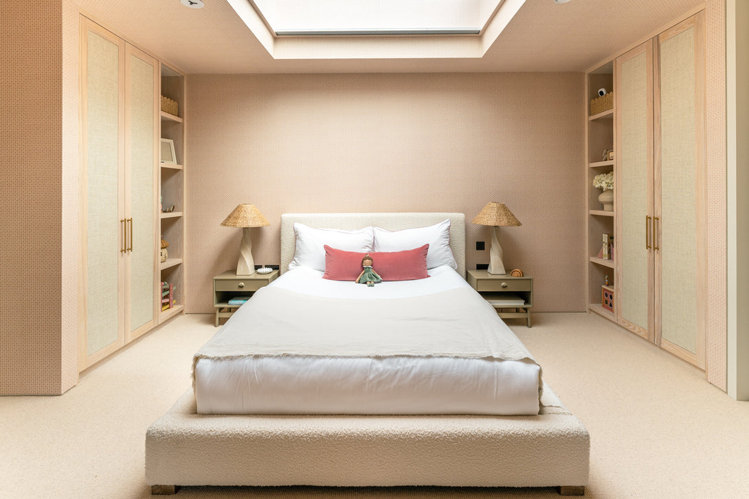A symmetrical view of the daughter's bedroom, showing the bed flanked by two bespoke light oak wardrobes with integrated display shelving.